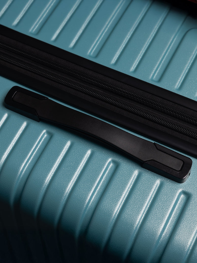 Close-up of a blue suitcase with a black handle