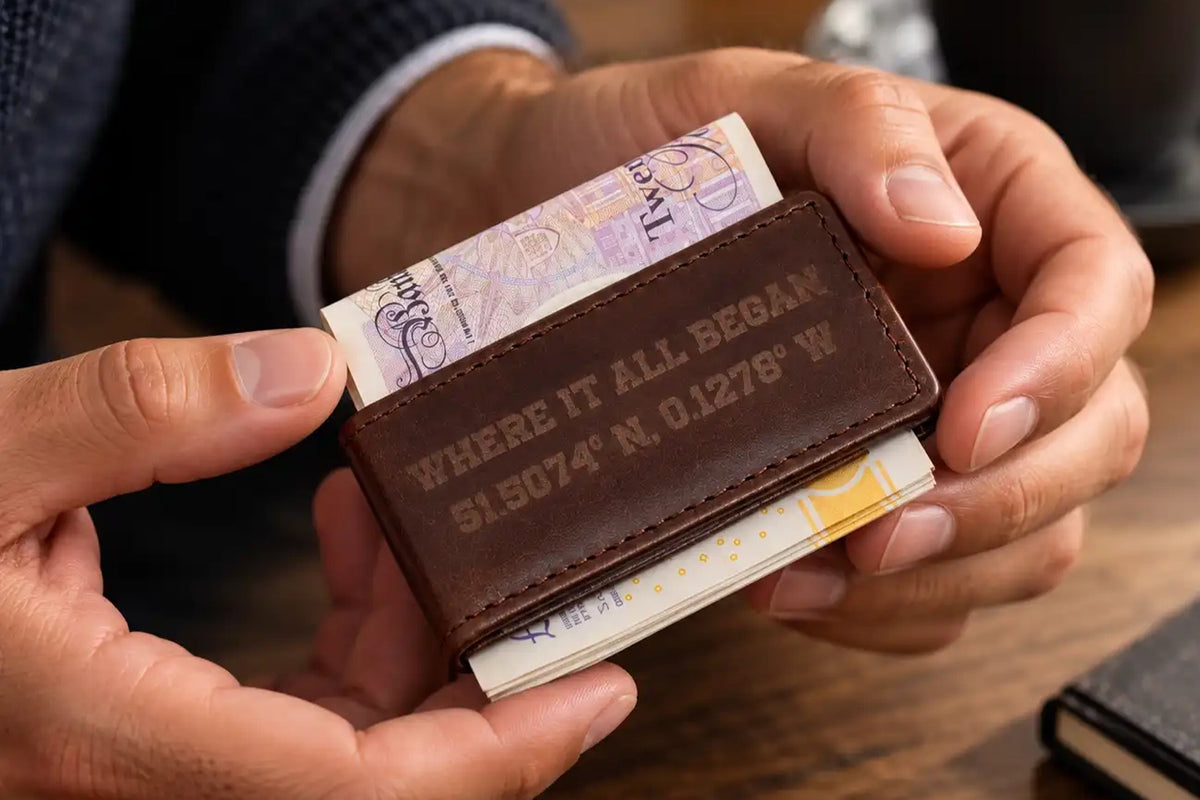 Personalised dark brown leather money clip held in hands with folded banknotes