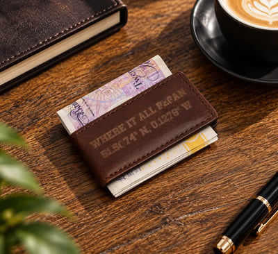 Dark brown magnetic leather money clip holding banknotes on wooden desk